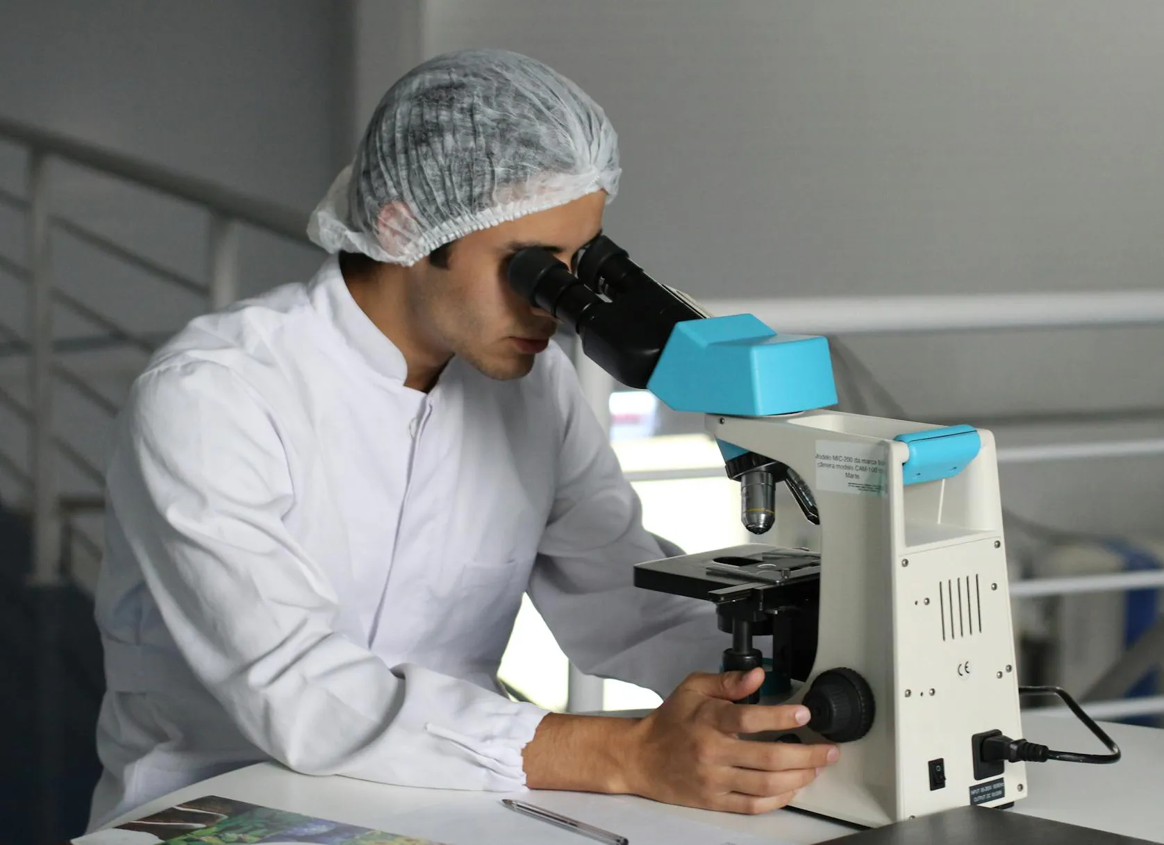 Persona in ambito farmaceutico che osserva al microscopio