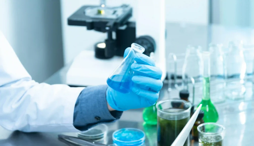 Persona che tiene una provetta in mano con guanto in laboratorio